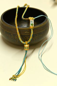 a close up of a necklace on a table with a bowl and other items in the background