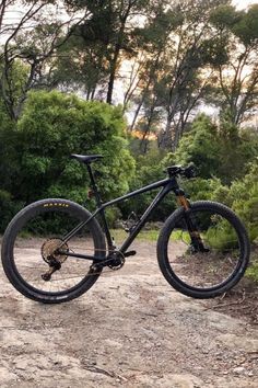 a black mountain bike parked on a dirt road