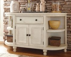 a white cabinet with drawers and shelves in front of a brick wall