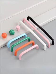 four different colored plastic handles on a white surface with an orange ball in the background