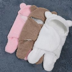 three pairs of teddy bear mittens laying on top of a blue blanket with pink, brown and white ones