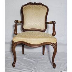 an old fashioned wooden chair with upholstered back and arm rests against a plain white backdrop