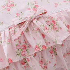 the pink bedding has roses on it and is ruffled with lace around the edges