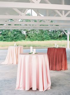 two tables with pink and red linens are set up for an outdoor wedding reception