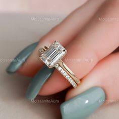 a woman's hand holding a ring with an emerald stone and diamond band on it