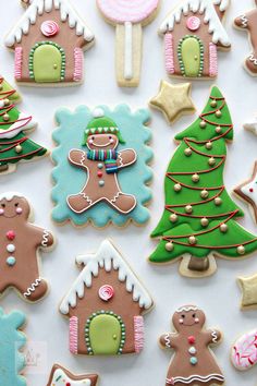 many decorated cookies are displayed on a white tablecloth with christmas trees and gingerbreads