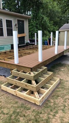 a wooden deck is being built in front of a house with white columns and pillars