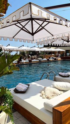 an outdoor swimming pool with lounge chairs and umbrellas