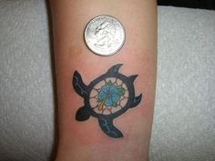 a small tattoo on the arm of a person with a coin in front of it