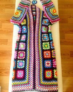 a colorful crocheted jacket is displayed on a table