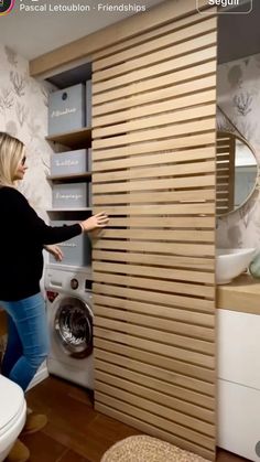 a woman standing in front of a washer next to a wall mounted dryer