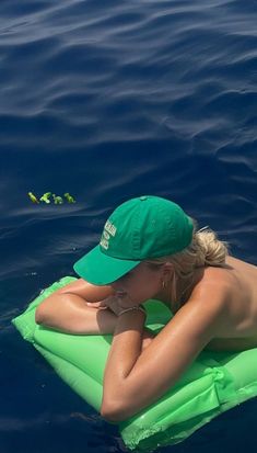 a woman wearing a green hat is floating on an inflatable raft with her hands behind her head