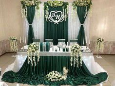 a wedding ceremony setup with green and white flowers on the table cloths, candles and decorations