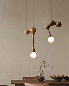 three wooden lights hanging from the ceiling above a table with chairs and bowl of fruit on it