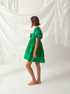 Elevate your wardrobe with our stunning Handsewn Floral Embellished Lauren Dress by Madeline Marie. This chic, handsewn dress features trendy puff sleeves, a flattering square neckline, and a tiered A-line silhouette. The vibrant green fabric and bow detail offer a playful, feminine touch perfect for garden parties, evening events, or casual outings. Dress it up with heels or keep it casual with sandals. Make a bold statement in this versatile and stylish mini dress! Spring Square Neck Puff Sleeve Dress With Tie Back, Green Mini Dress With Ruffle Hem And Square Neck, Summer Mini Dress With Gathered Sleeves And Straight Neckline, Green Puff Sleeve Dress With Gathered Sleeves, Fitted Tiered Puff Sleeve Dress With Gathered Sleeves, Chic Puff Sleeve Dress With Tiered Skirt, Chic Puff Sleeve Dress With Ruffles And Square Neck, Elegant Summer Puff Sleeve Dress With Tiered Skirt, Chic Fitted Puff Sleeve Dress With Tiered Skirt