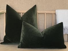 two green pillows sitting on top of a bed next to a white towel and potted plant