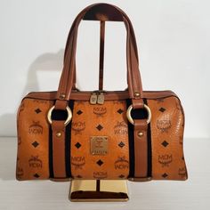 Shop jachzette09's closet or find the perfect look from millions of stylists. Fast shipping and buyer protection. Vintage MCM Top Handle Bag Size: Small Measurement: 12.5" (L) x 6" (H) Color: Brown Printed Visetos Antiqued Gold Brass Hardware Leather Trim Flat Handles Leather Trim Embellishment Logo Jacquard Lining & Three Interior Pockets Zip Closure at Top White Tag - Made in Korea NO DUST BAG Note: Please understand that this bag have been pre-owned, used and loved over many years and will Brown Monogram Canvas Top Handle Shoulder Bag, Brown Monogram Canvas Bag With Detachable Strap, Brown Monogram Canvas Bag With Top Carry Handle, High-end Brown Shoulder Bag With Gold-tone Hardware, Evening Satchel With Detachable Strap In Monogram Canvas, Evening Monogram Canvas Satchel With Detachable Strap, High-end Brown Satchel With Gold-tone Hardware, Designer Monogram Canvas Satchel For Evening, High-end Brown Shoulder Bag With Leather Handles