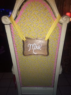 a decorated chair with the word mrs on it's back and yellow ribbon around the seat