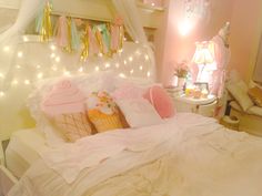 a pink bedroom with fairy lights on the ceiling and bed in the foreground, an ice cream cone at the end of the bed