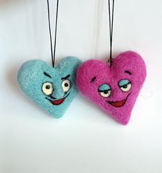 two felt hearts with faces hanging from strings