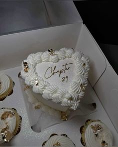 a heart shaped cake in a box surrounded by cupcakes