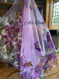 three purple and white scarfs are hanging on a rack in front of a window