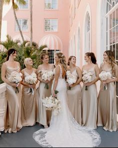 a group of women standing next to each other in front of a building with palm trees