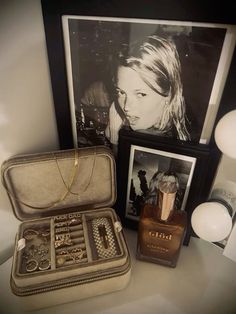 an open suitcase sitting on top of a table next to a framed photo and jewelry