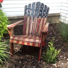 a wooden chair sitting in the middle of a yard with an american flag painted on it