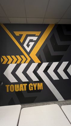 a gym wall with arrows painted on it and the words tough gym written in yellow