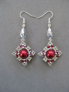 pair of red and clear beaded earrings with crystal drops on grey background, closeup