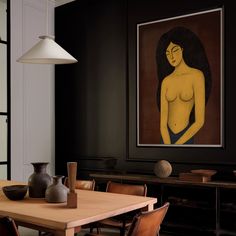 a painting hangs on the wall next to a wooden table with chairs and vases