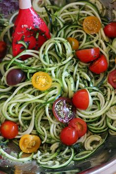 a bowl filled with zucchini noodles, tomatoes and other veggie ingredients