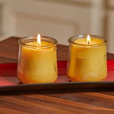 two candles sitting on top of a red tray