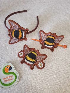 three wooden bee headbands with embroidered designs on them