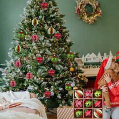 two children are sitting in front of a christmas tree