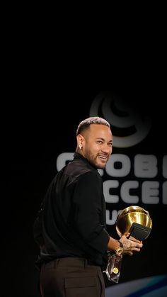 a man holding an award in his hand and smiling at the camera while standing on stage