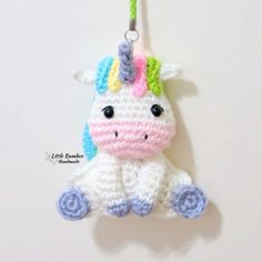 a crocheted unicorn ornament hanging from a hook on a white wall