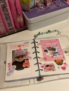 an open planner book on a table next to some pink and white books with teddy bears