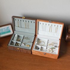 two wooden boxes filled with jewelry sitting on top of a table next to a framed photograph