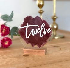 there is a small wooden block with the word tweefe on it and flowers in the background