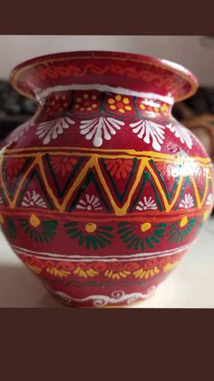 a red and yellow vase sitting on top of a table