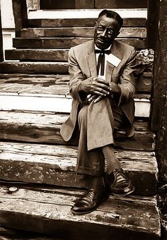 a man in a suit and tie sitting on some steps with his hands folded up