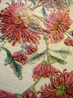 some pink flowers on a white cloth with green leaves and stems in the middle,