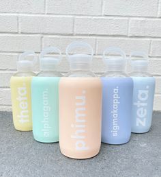 four water bottles with the word'zero'printed on them, lined up against a white brick wall