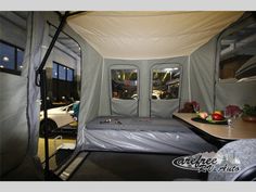 the interior of a camper trailer with its bed and windows covered in tarp