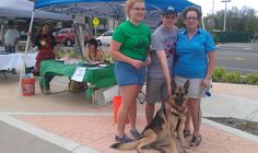 three women and a dog standing under a tent