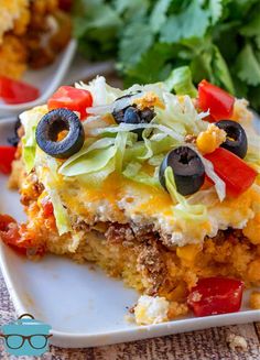 a slice of mexican casserole on a plate with lettuce and tomatoes