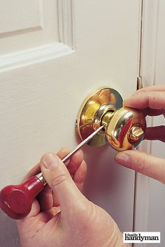 a person is opening a door with a red handle and screwdriver in their hand