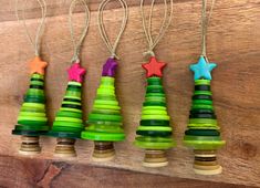 four christmas tree ornaments hanging from strings on a wooden board with string attached to them